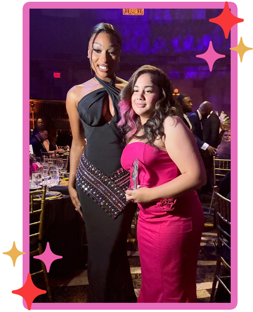 Mila holding an award and standing with Megan Thee Stallion at a formal event celebrating youth leadership and mental health advocacy.